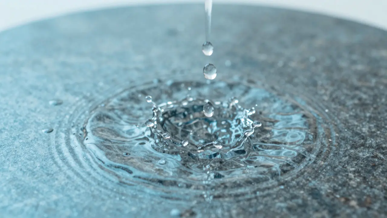 Macro shot of water droplets hitting a stone surface, symbolizing ritual cleansing and hygiene